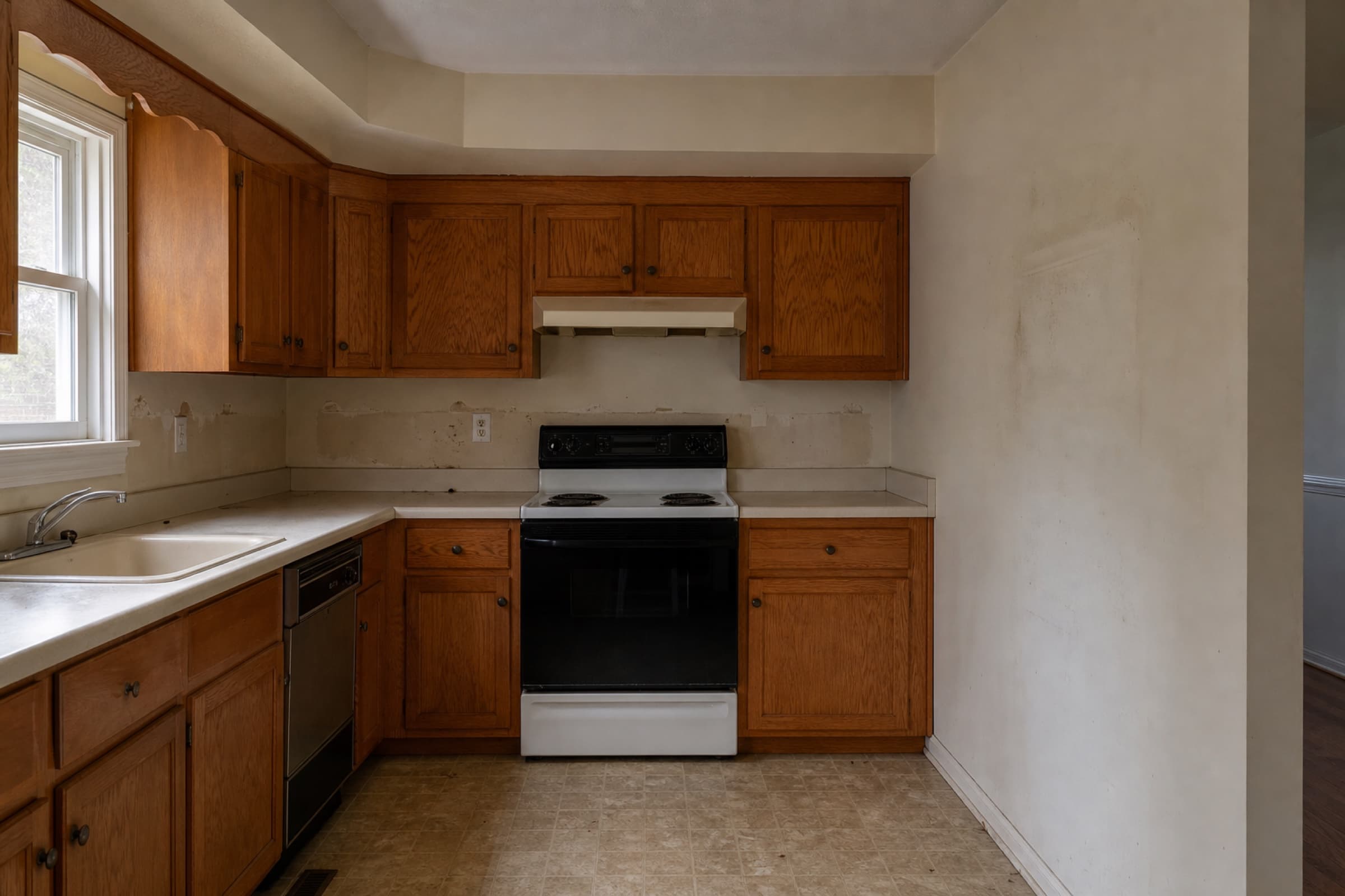 Dated oak wall cabinets and laminate counters in a closed kitchen, with a soffit above the run