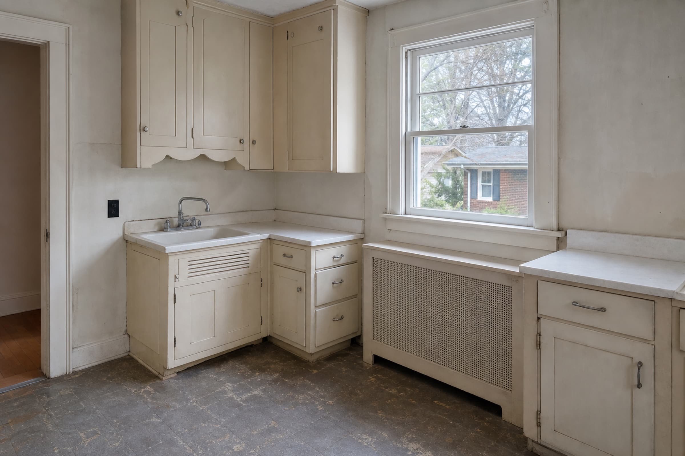 A small 1930s kitchen with a mix of later cabinets in two different styles and a boxed-in radiator